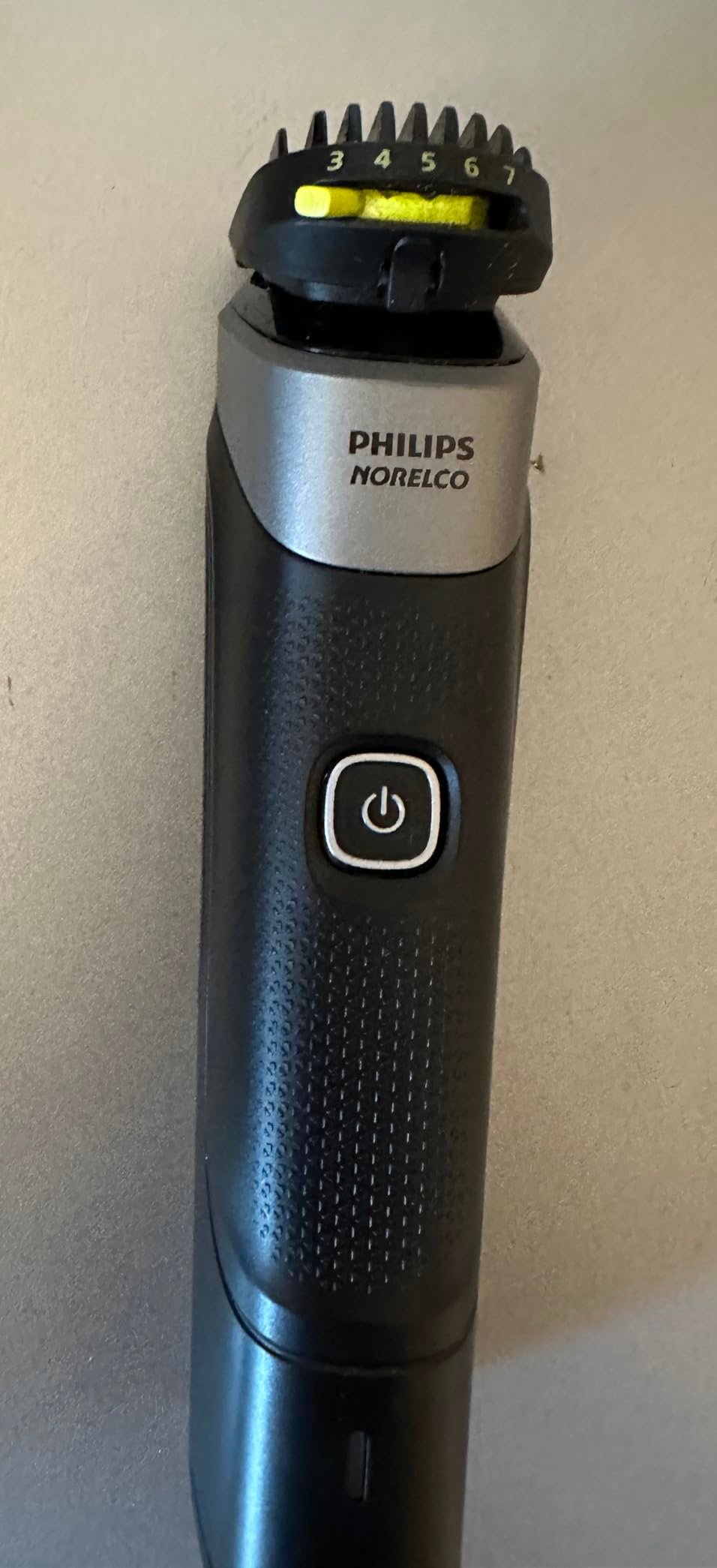 Philips Norelco Multigroom 5000 in use showing trimmer head detail and 18-piece kit